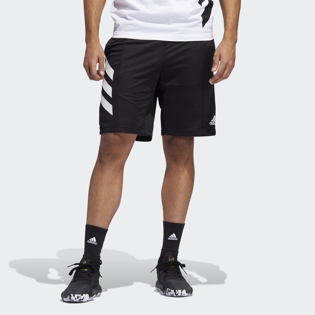 Person i svarta träningsshorts med vita ränder på sidorna, fotograferad stående mot vit bakgrund.